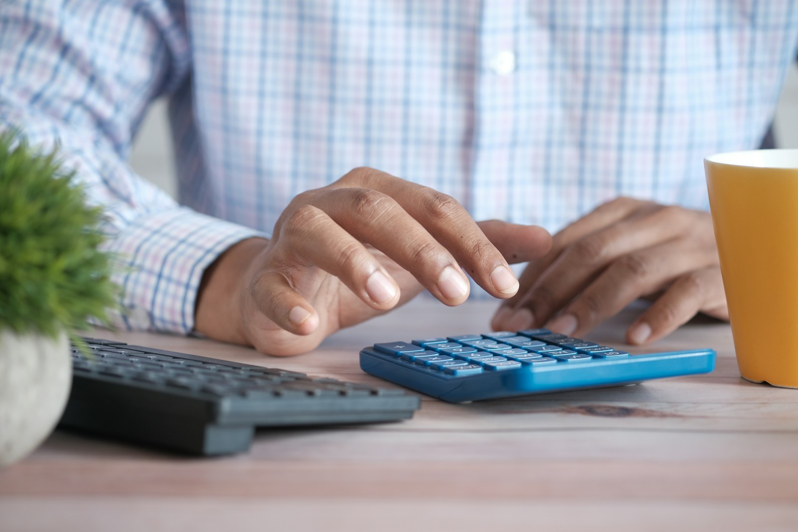 Hand using a calculator to budget for rising 2027 health insurance premiums